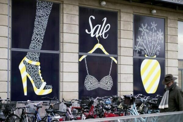 3 yellow and black posters on shop windows advertising a sale