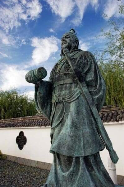 A monument of strategist Sun Tzu outdoors against white wall
