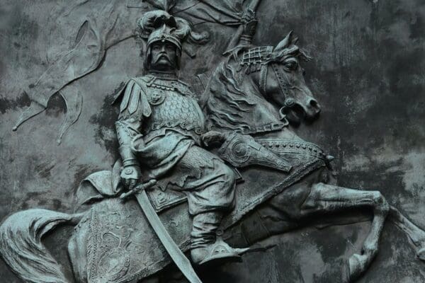 Stone statue of Sun Tzu riding a horse against a stone background