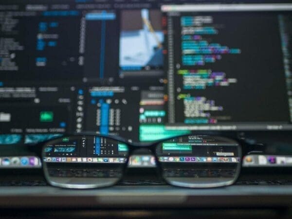 A pair of glasses in front of a computer screen with colorful code