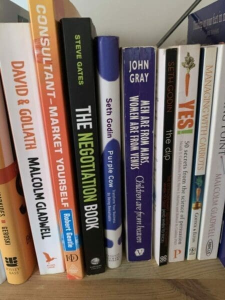 Spines of several negotiation and self-improvement books on a book shelf