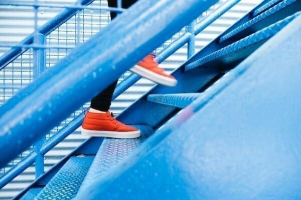Feet wearing red sneakers running up blue stairs