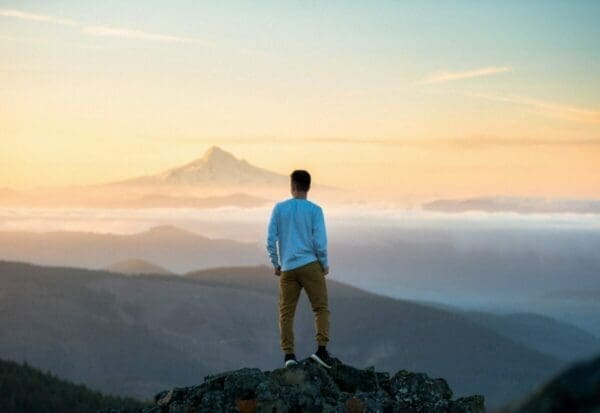 Man standing on top of a mountain looking out at the horizon for relaxation