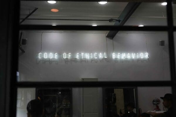 neon sign above a store saying Code of Ethical Behaviour