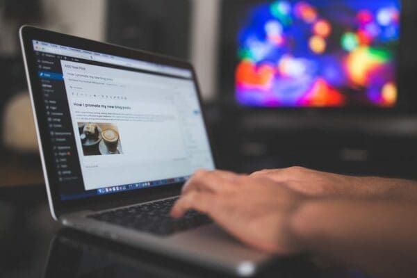 Man's hand editing a WordPress post on a laptop