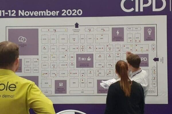 3 people looking at a CIPD chart on the wall during a CIPD conference