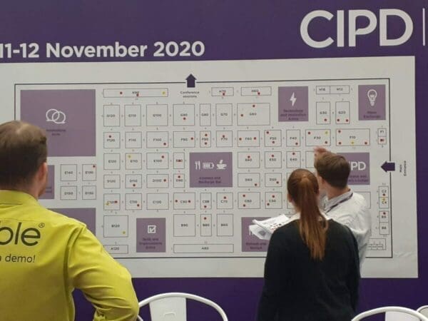 3 people looking at a CIPD chart on the wall during a CIPD conference