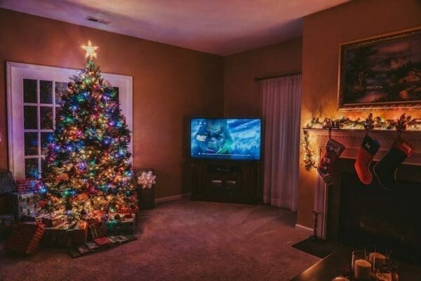 Cozy living room with Christmas tree and stockings on fireplace and a television