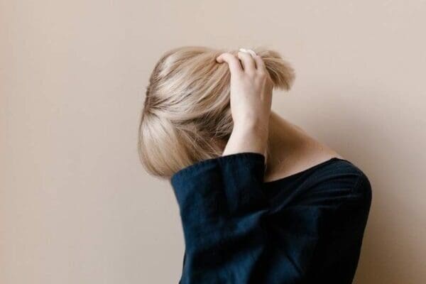 Shy woman with blonde hair and head bowed
