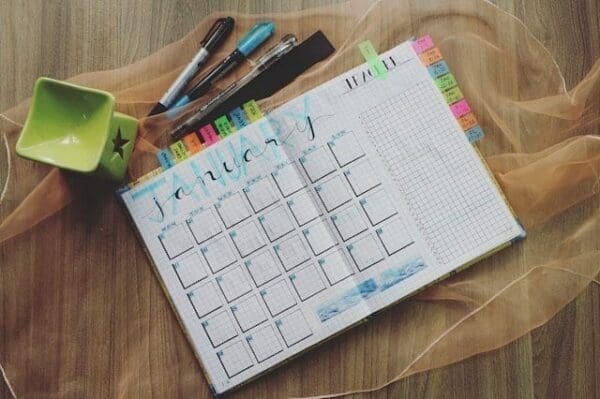 Planner with multicoloured tabs on a table with pens