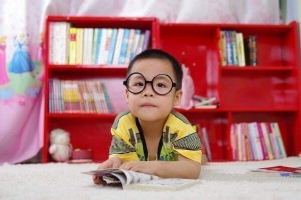 A young boy with glasses reading a book