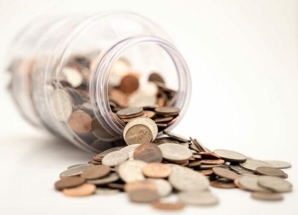 Toppled open jar with coins scattered outside of its rim 
