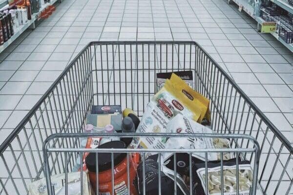 Inside a half full metal trolley in the middle of supermarket isle
