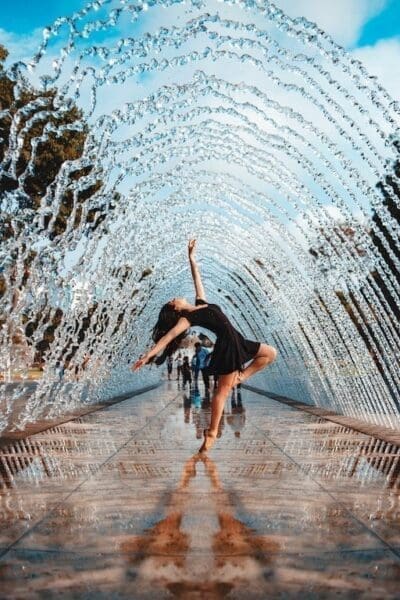 Woman dancing under an arch of water symbolising self-confidence