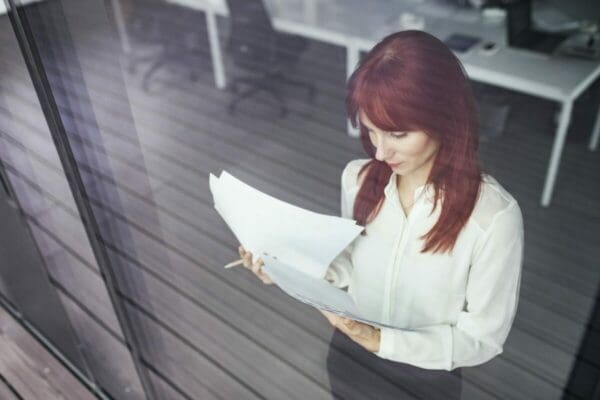 Associate businesswoman reads documents at the window in her office 