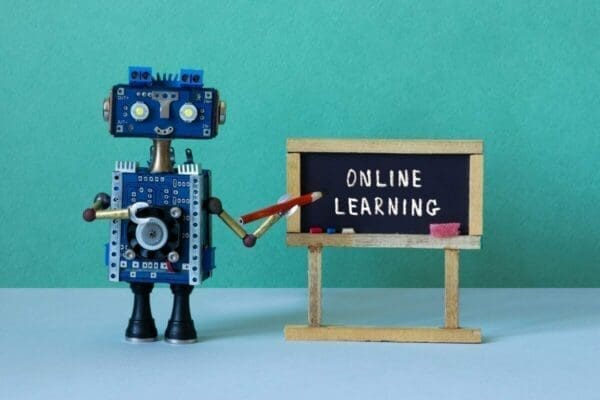 Blue robot pointing to a blackboard that has Online Learning written on it