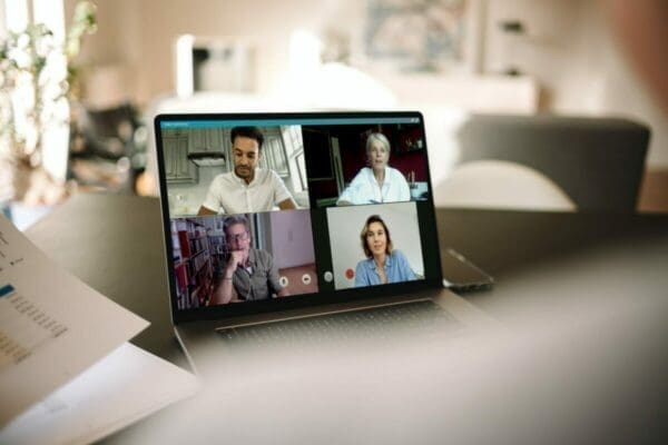 Laptop showing four business persons during a video call while working from home