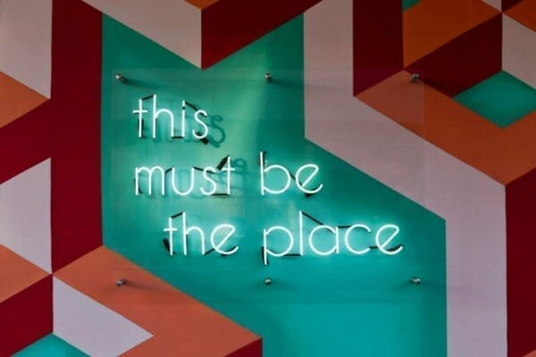 Lit up text 'This Must Be The Place' against a patterned wall