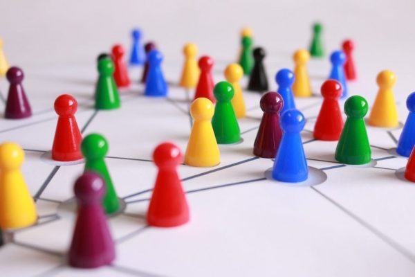 Multi-coloured plastic counter pieces on a white sheet with a web drawn on - communicating and influencing connections