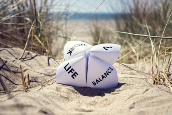 Paper fortune teller showing work life balance on the sand with beach in the background
