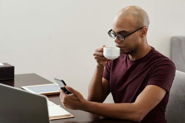 Man checking notifications on his phone while drinking coffee