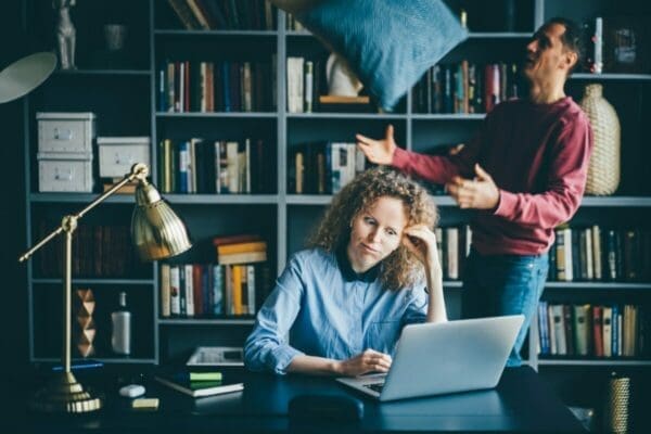 Woman working from home is distracted by a man in the background 
