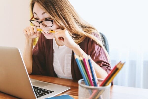 Woman at her desk biting pencil trying to create L&D content