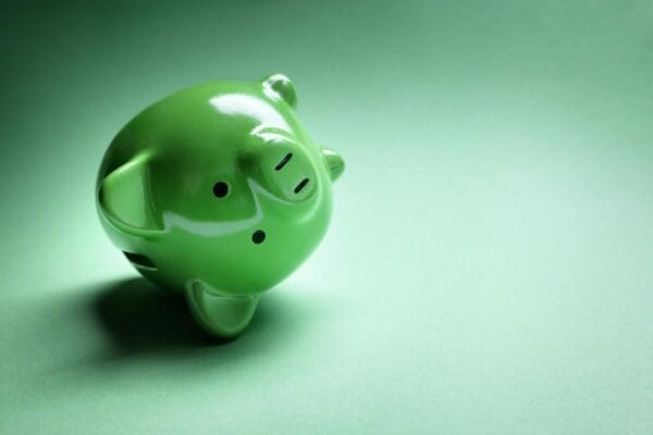 Green piggy bank on its side on a green background