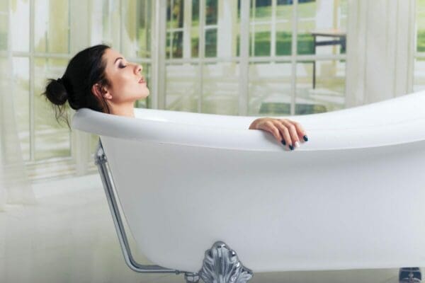 Woman relaxing in a bath with her head back and eyes closed for self-care