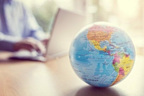 Globe on a table with a businessman in the background represents cross cultural communication