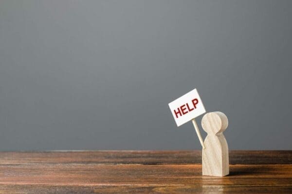 Wooden figure holding a sign that says help represents asking for help