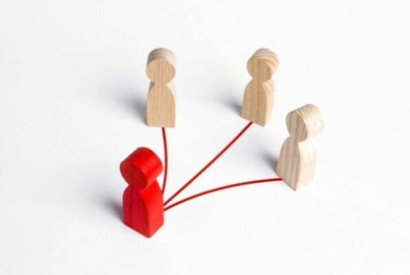 Wooden figures following a red figures in leadership