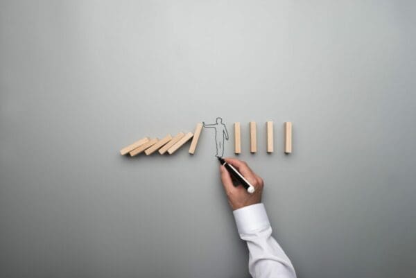 Man drawing the outline of a businessman stopping the domino effect
