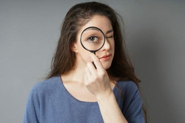 Female category detective looking through a magnifying glass