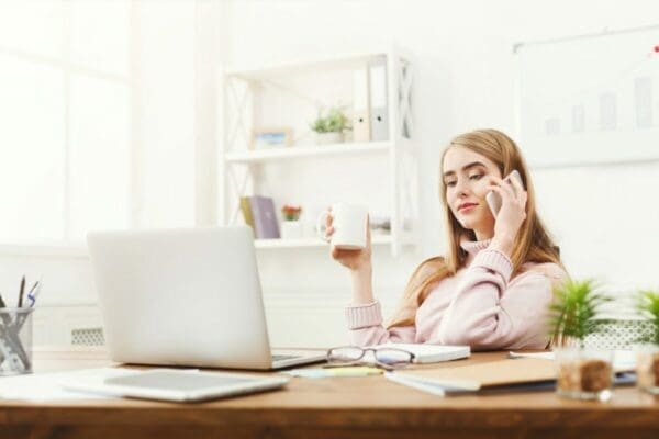 Woman working from home while accepting a call and drinking coffee