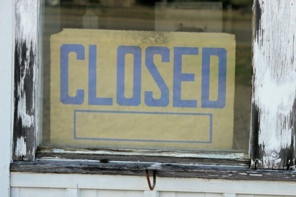 Closed sign with blue letters behind a glass window