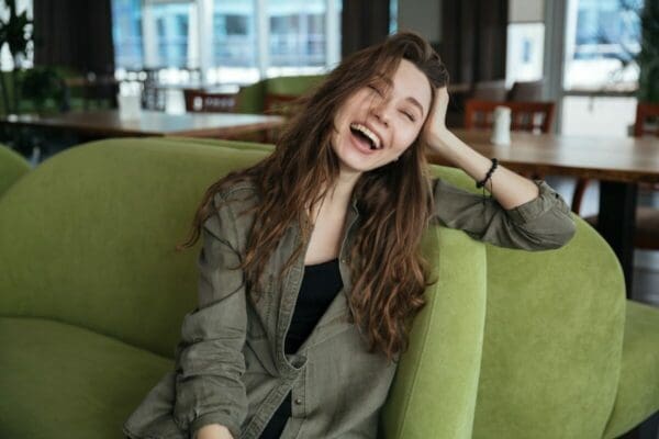 Woman on green sofa laughing 