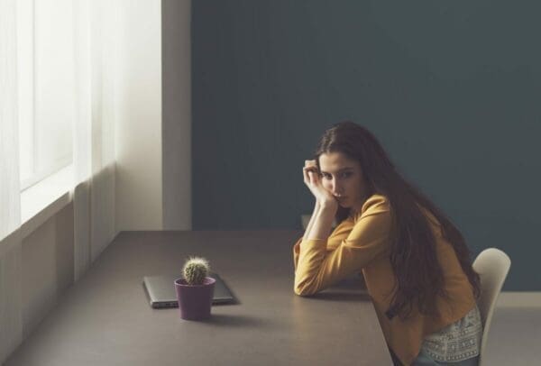 Sad lonely young woman working at home misses office gossip