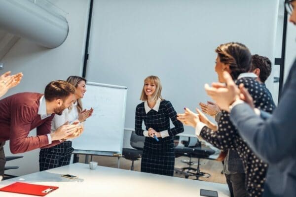 A group of business people clapping a woman giving a presentation