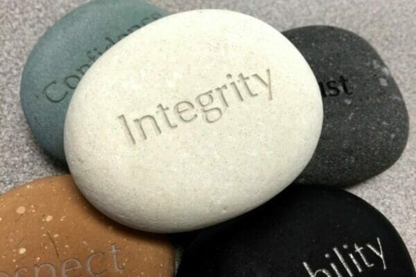 Five stones with different words on, the top stone says Integrity