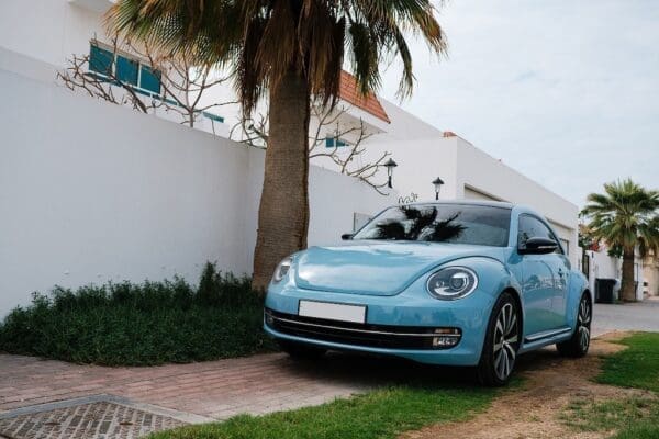 Blue VW beetle Parker outside a white house with palm trees