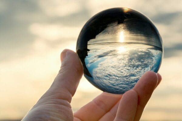 Hand holding a clear ball reflecting the sea and cloudy sky represents clear communication