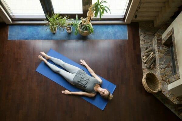 Woman laying on her back on a yoga mat to improve her mental health