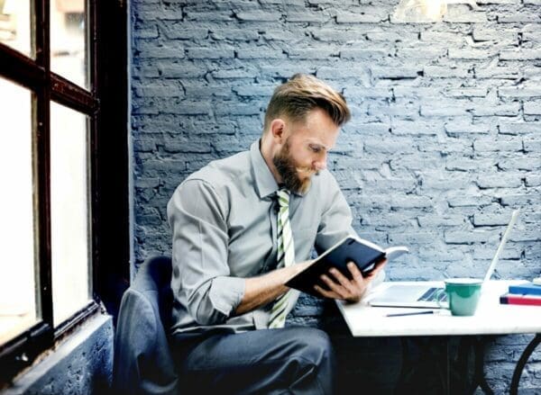 Businessman at desk looking at a notebook is thinking strategically