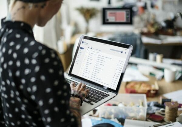 Businesswoman in black polka dot shirt checking her email inbox on a laptop
