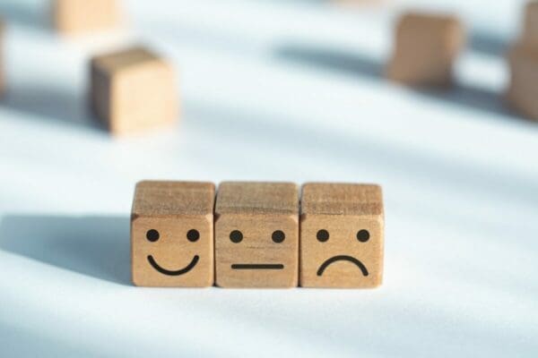 Three wooden cubes with happy, sad and neutral faces
