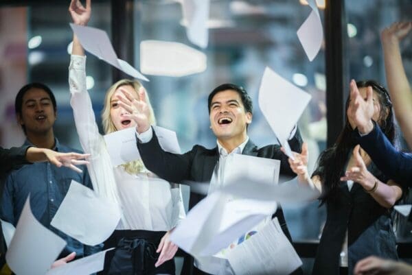 A group of businesspeople are throwing papers into the air to celebrate success