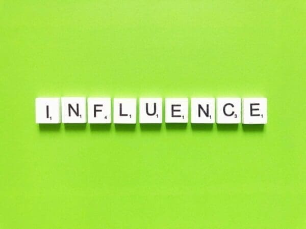 Influence spelled with word scramble tiles on green background