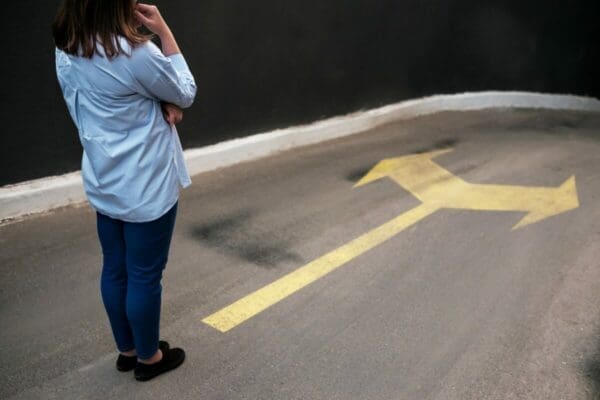 Young woman at a dead end deciding whether to follow the right or left arrow represents decision making