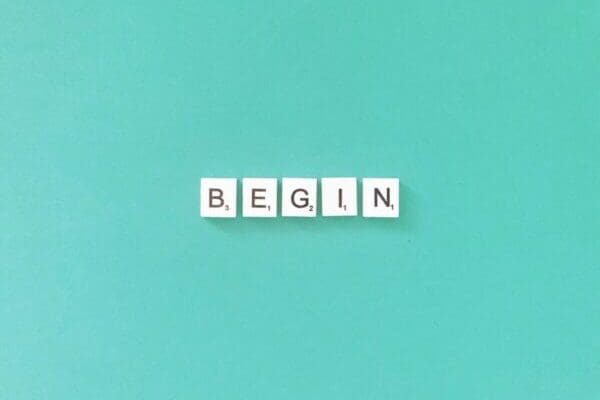 Begin spelled with white word scramble tiles on light blue background
